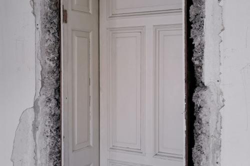 weiß getäfelte Holztür in einem abgebrochenen weißen Gemäuer