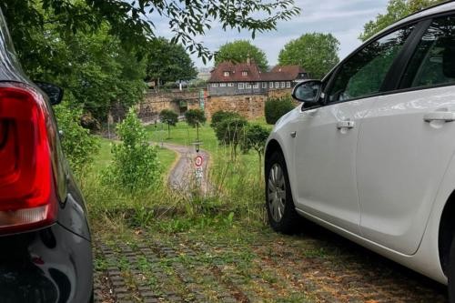 Autos parken auf dem Parkplatz neben der Mülbergerstraße, im Hintergrund die Burg