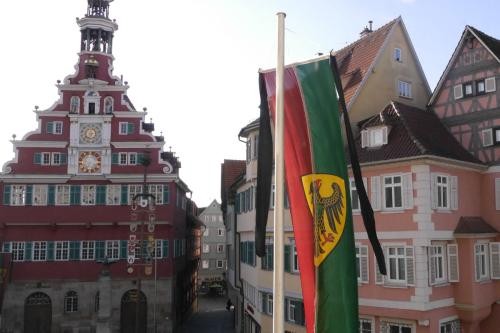 Rot-grüne Flagge mit dem Esslinger Stadtwappen hängt mit schwarzem Trauerflor vor dem Neuen Rathaus