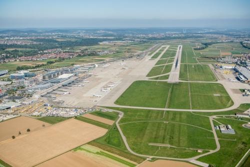 Luftbild des Flughafens Stuttgart, zu sehen ist die Start- und Landebahn, rechts im Bild die Terminals und im Hintergrund am Horizont Esslingen