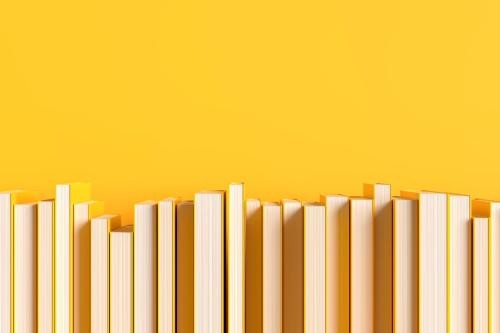 gelb eingebundene Bücher stehen mit der Schnittseite nach vorne vor einer gelben Wand 