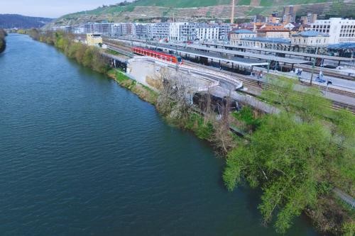 Blick auf die Baustelle des Neckaruferparks aus der Luft, im Vordergrund der Neckar, im Hintergrund die Bahngleise