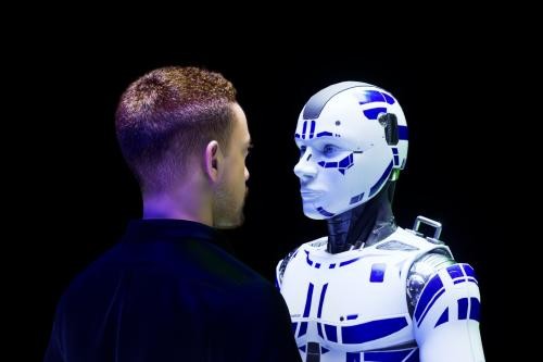 Mann und humanoider Roboter stehen sich einander gegenüber