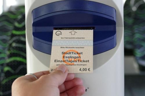 Ein Mensch hält ein Stadtticket als Papierticket in einem Bus
