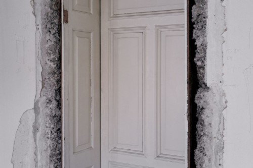 weiß getäfelte Holztür in einem abgebrochenen weißen Gemäuer