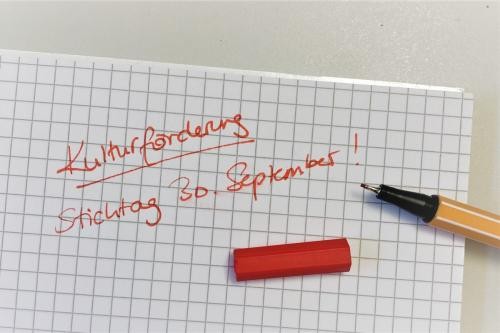 karierter Block, roter Stift, Text: Kulturförderung Stichtag 30. September!