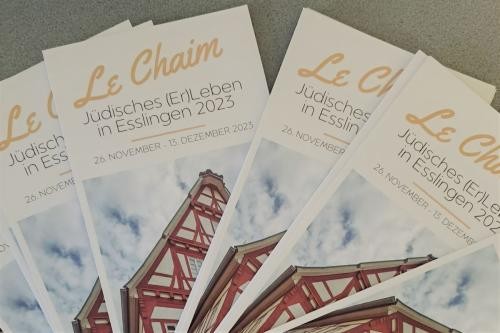 mehrere Flyer mit der Aufschrift "Le Chaim - Jüdisches (Er)Leben in Esslingen 2023". Auf dem Titel der Broschüren ist ein Gebäude mit rotem Fachwerk zu sehen.
