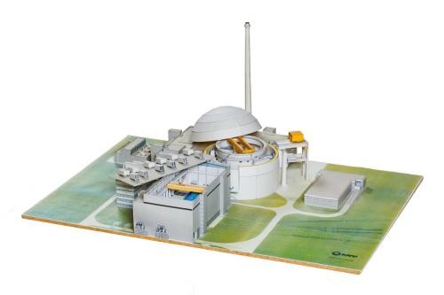Papiermodell eines Atomkraftwerks auf grünem Untergrund. Die Dächer des Reaktorgebäudes und des Maschinenhauses sind geöffnet.