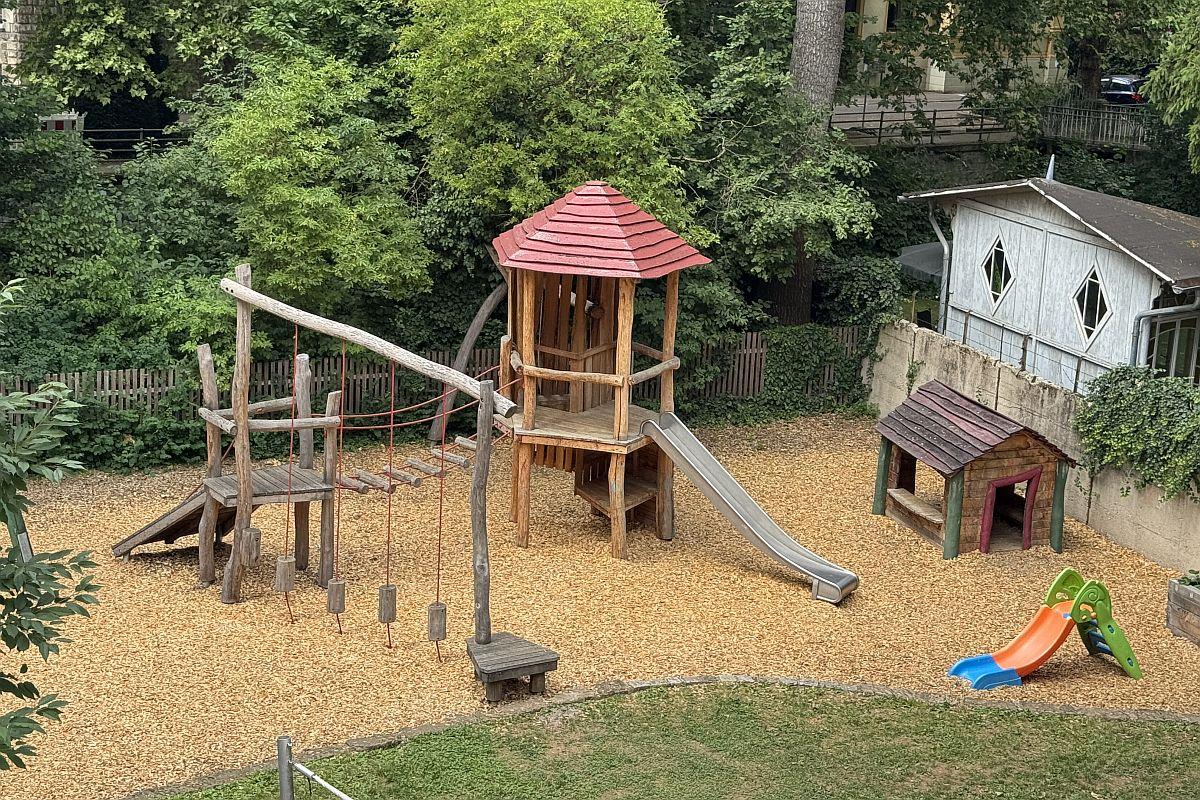 Der Garten mit Kletteranlage, Spielturm, Rutsche und Spielhaus in der städtischen Kita Merkelstraße