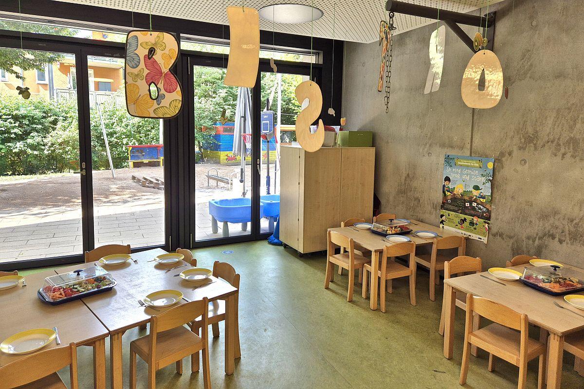 Der Mehrzweckraum mit gedeckten Tischen und Stühlen für die Kinder in der städtischen Kita Birkenweg