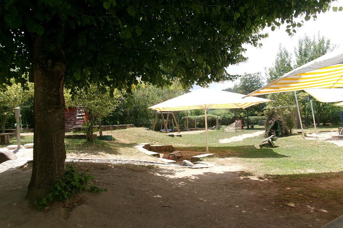 Der Sandkasten-Bereich mit Sonnenschirme im Garten der städtischen Kita Auenweg