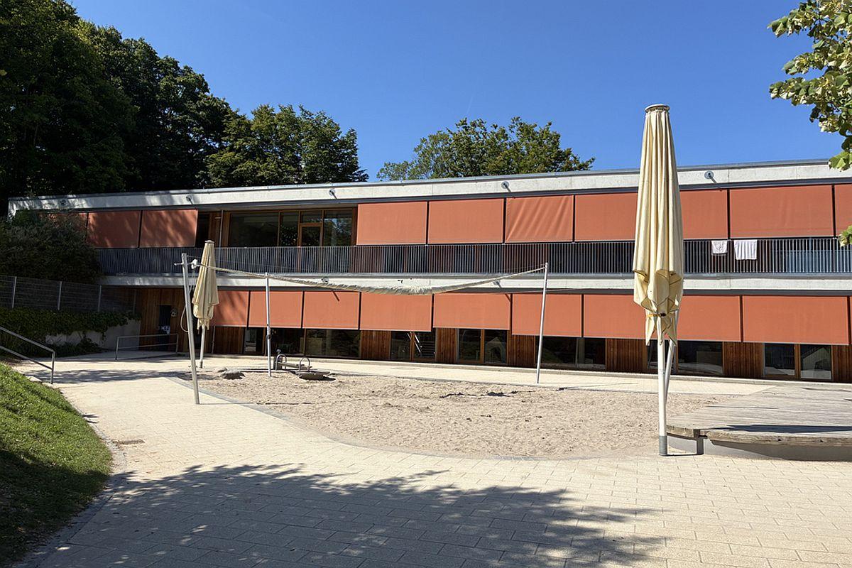 Der Sandkasten im Außenbereich der städtischen Kita Goerdelerweg mit Kita-Gebäude im Hintergrund
