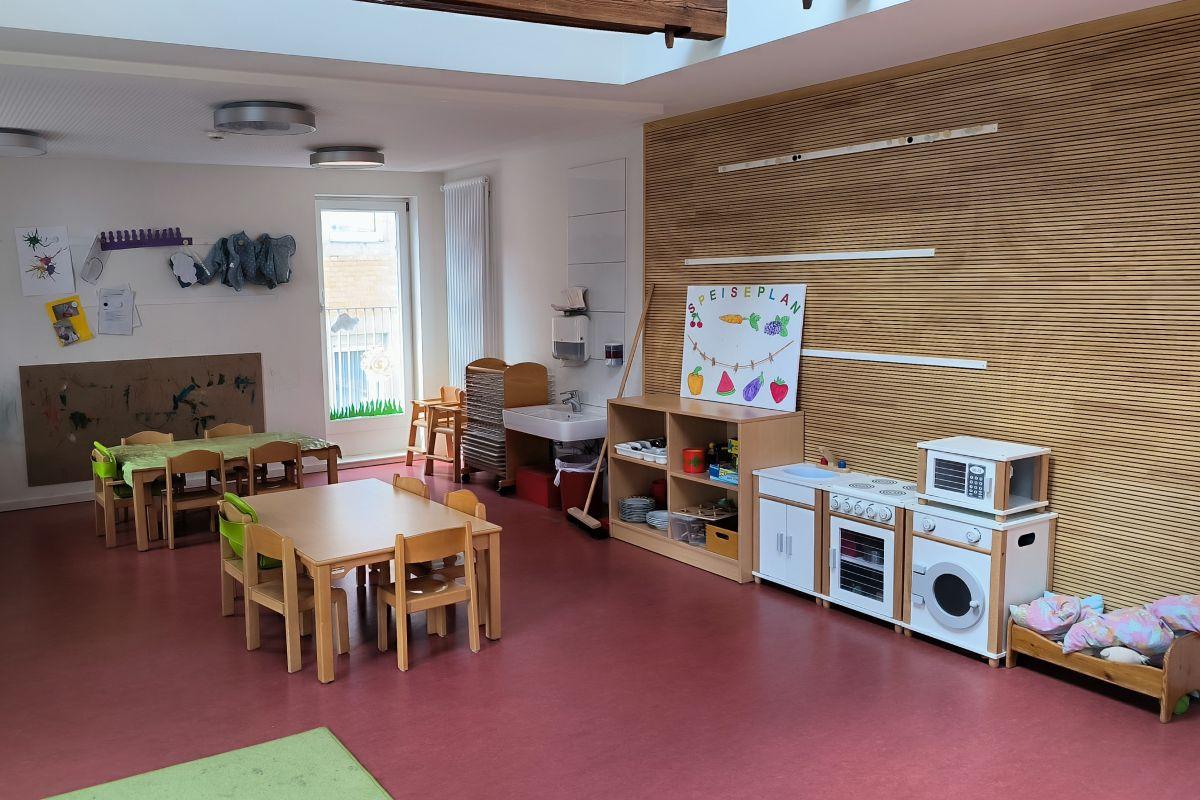 Die Tische mit Stühlen und die Spielküche in der Krippe der städtischen Kita Uhlandstraße