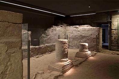 Mittelalterliche Ausgrabungen, z. B. zwei Säulenbasen, in einem abgedunkelten Raum
