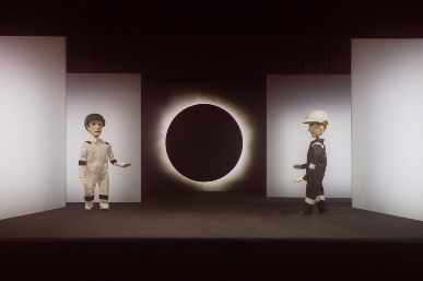 Zwei Marionetten befinden sich vor einem hell-dunklem Hintergrund