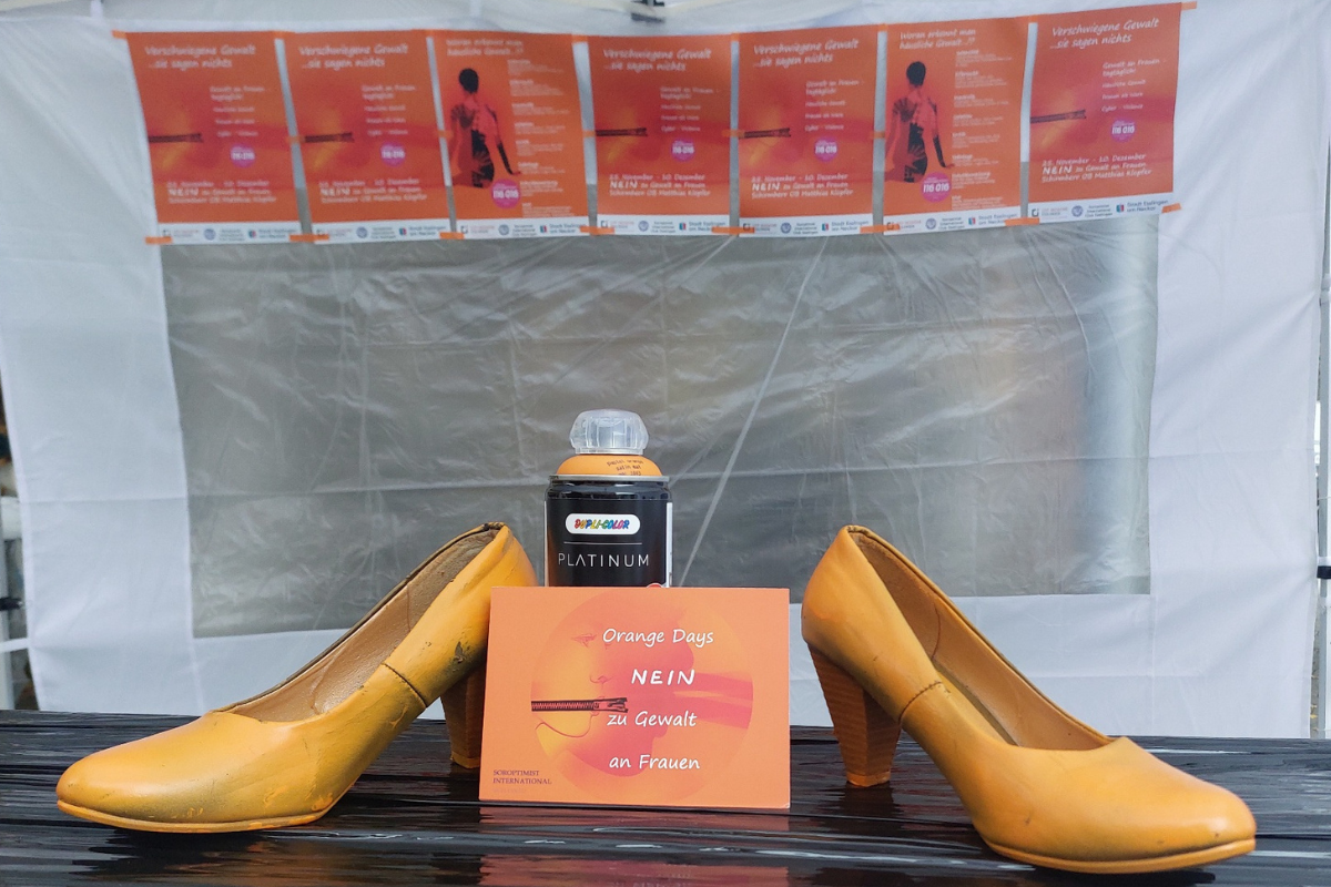 Orange Days Zu sehen sind orange angesprühte Damenschuhe und eine Postkarte mit der Aufschrift "Nein zu Gewalt an Frauen"