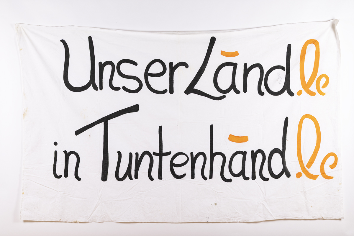 Banner mit der Beschriftung: Unsere Land in Tuntenhand, in anderer Farbe ergänzt zu: Unser Ländle in Tuntenhändle.