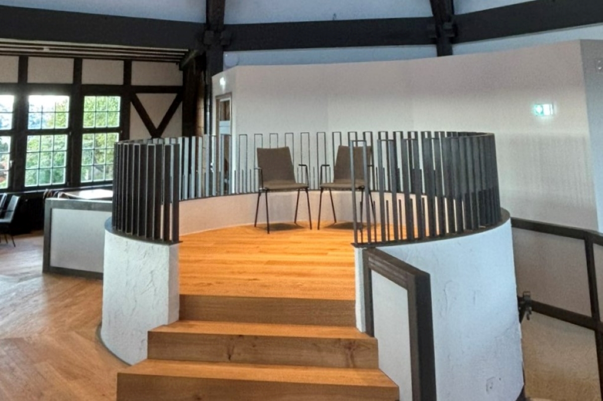 Dicker Turm, Bühne im Turmsaal © Stadt Esslingen am Neckar Blick in einen achteckigen Raum, links hinten sind Fenster zu sehen. In der Mitte des Raums ein rundes Podest, zu dem Stufen emporführen und das mit einem Geländer umzäunt ist. Auf dem Podest stehen zwei Stühle