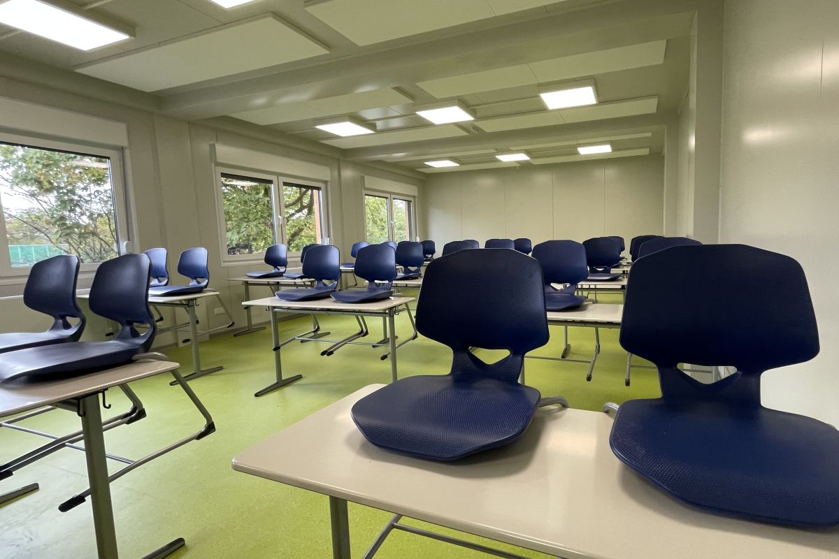 Blick ins Klassenzimmer mit grünen Boden und dunkelblauen Stühlen