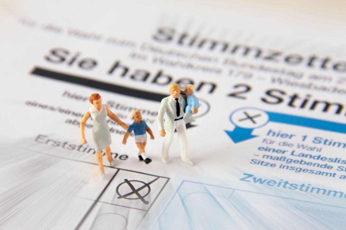 Familie aus Spielfiguren steht auf einem Stimmzettel