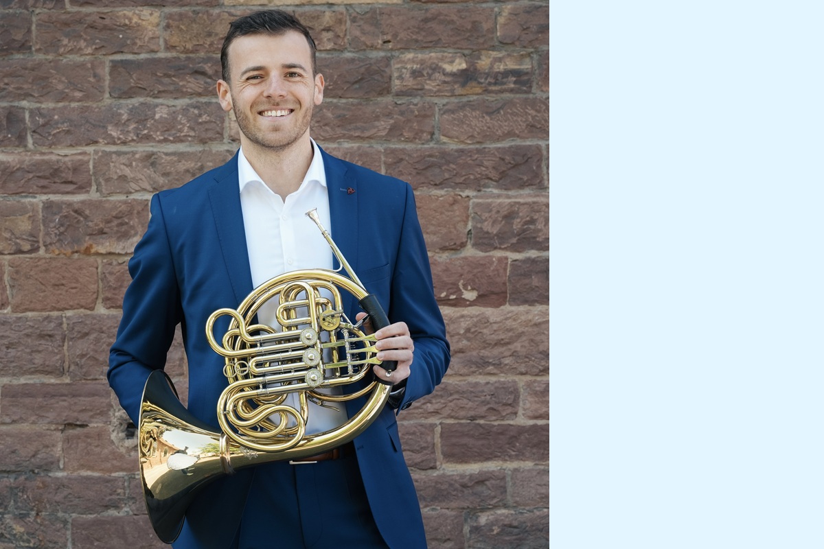 Portraitfoto Mathias Stelzer mit Horn vor einer Mauer