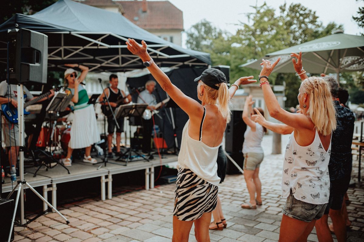 Band beim Schwörfest ©Sabine Watzko Menschen tanzen fröhlich vor einer Liveband auf einer kleinen Bühne bei einem sommerlichen Straßenfest.