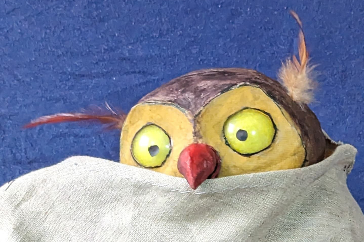 Kauz und Kekse Eine Eulen-Puppe ist halb hinter einem Tuch versteckt.
