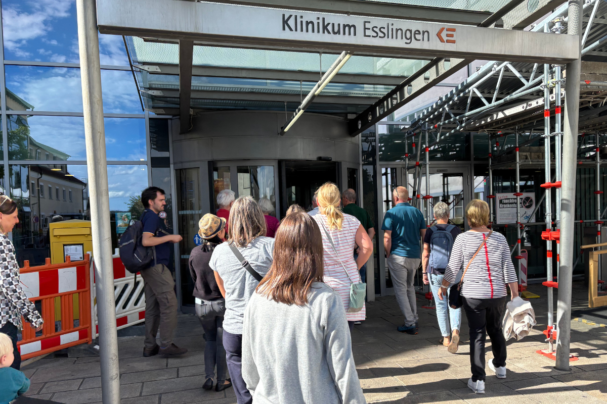 Hier entsteht bald eine neue Cafeteria. Gruppe läuft durch den Klinikeingang