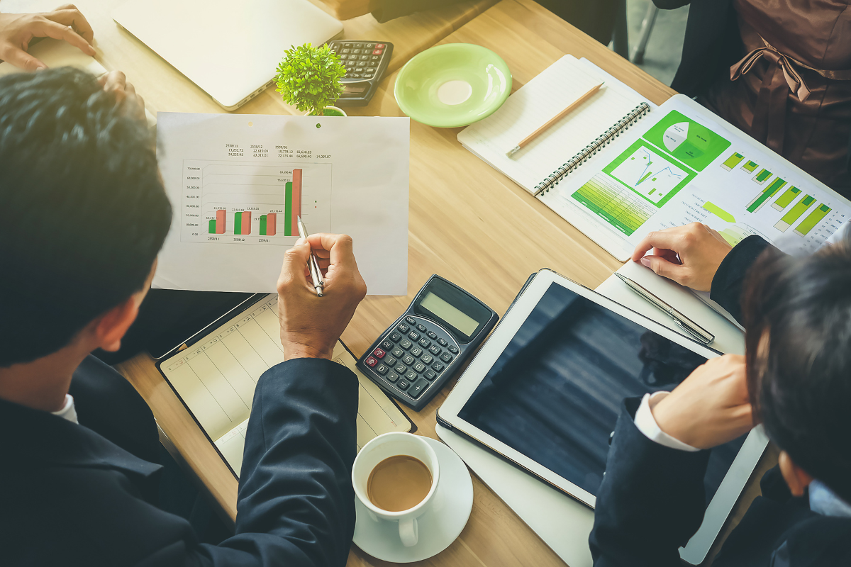 Zwei Menschen sitzen für eine Beratung am Tisch und blicken auf Diagramme