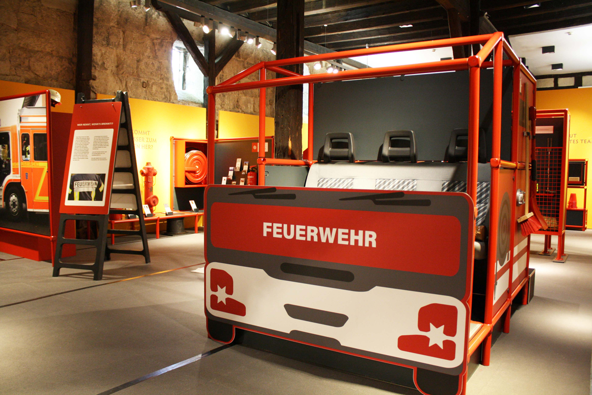 Ausstellungsraum "Wer rennt, wenn's brennt?" mit großem Modell eines Feuerwehrautos. Ausstellungsraum "Wer rennt, wenn's brennt?" mit großem Modell eines Feuerwehrautos.