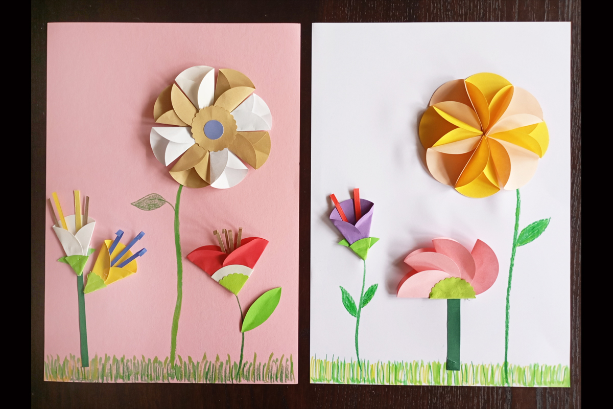 Einen Blumenwiese auf einer Karte: Die Blüten sind unterschiedlich aus buntem Papier gefaltet, die Blumenstiele und das Gras gemalt.