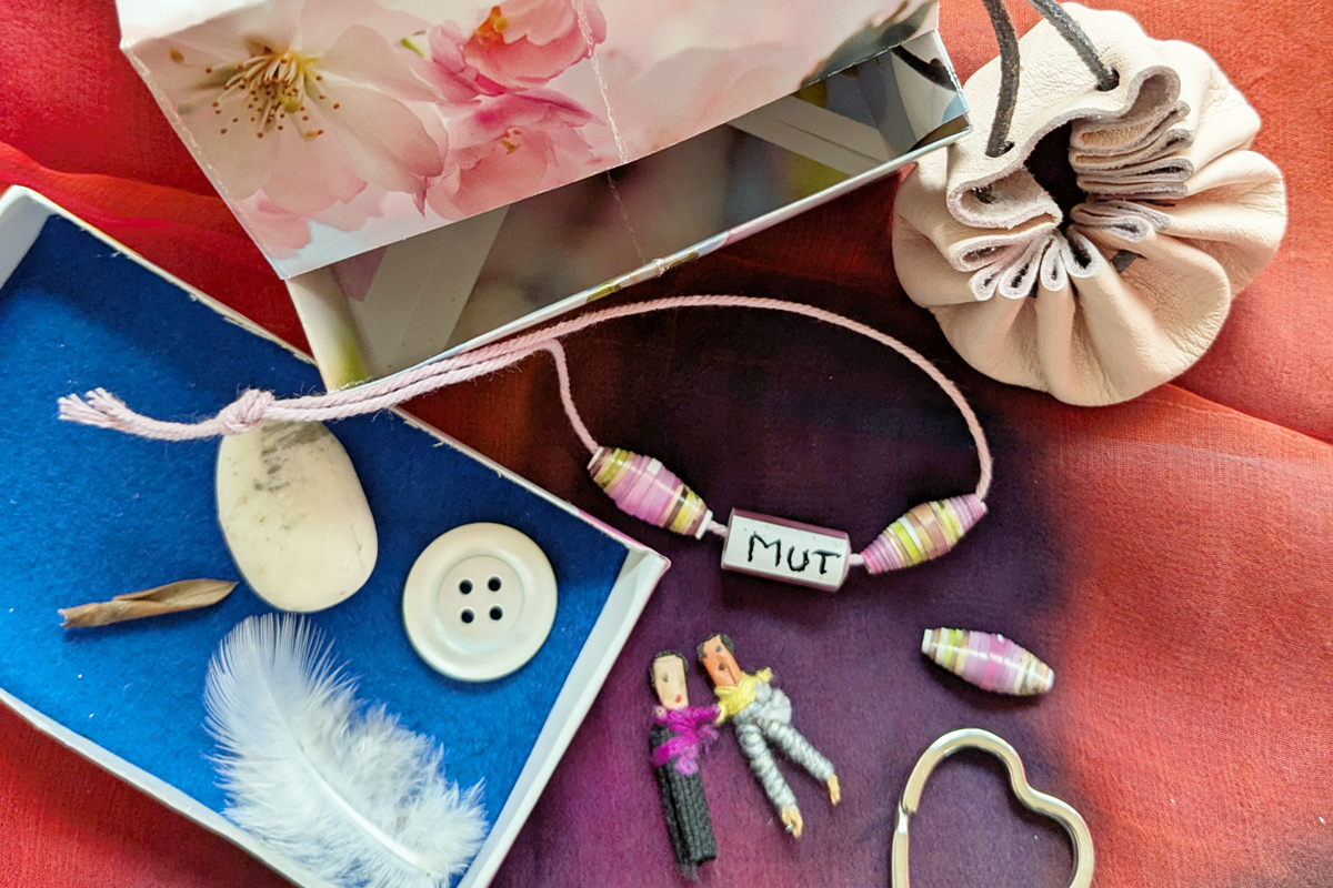 Kleine Puppen und ein Armband mit Perlen und der Beschriftung "Mut" Kleine Puppen und ein Armband mit Perlen und der Beschriftung "Mut"