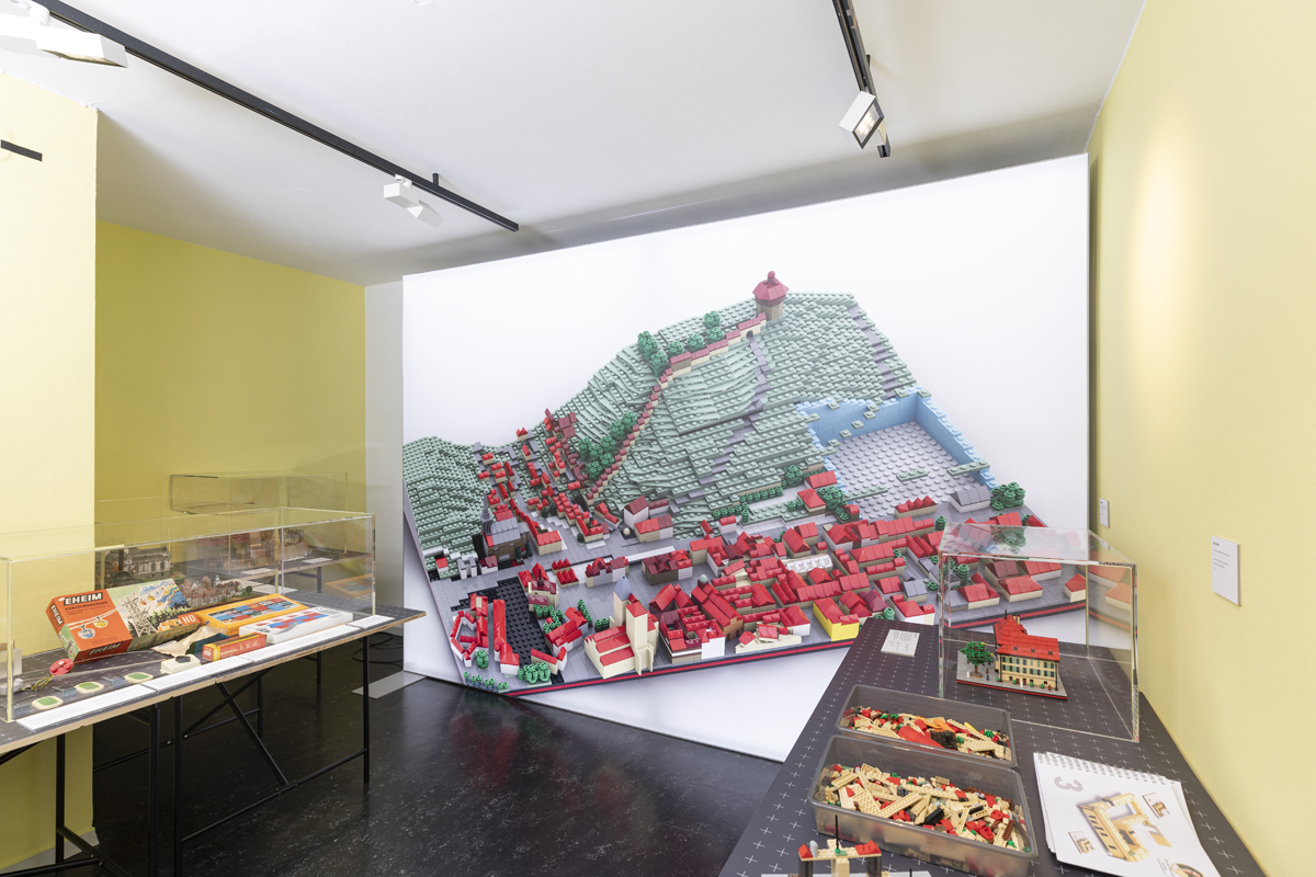 Tische mit Schalen voller Klemmbausteine, ein Modell des Gelben Hauses als Vorbild. Im Hintergrund ein wandgroßes Leuchtbild eines Bausteinmodells von Esslingen.