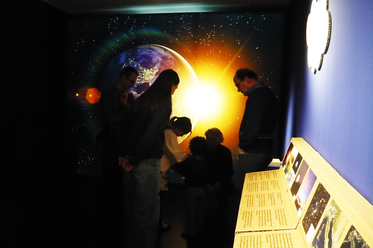 In der Mitmachausstellung "nachtaktiv" im Stadtmuseum im Gelben Haus. Menschen stehen vor einem wandgroßen Bild einer aufgehenden Sonne.