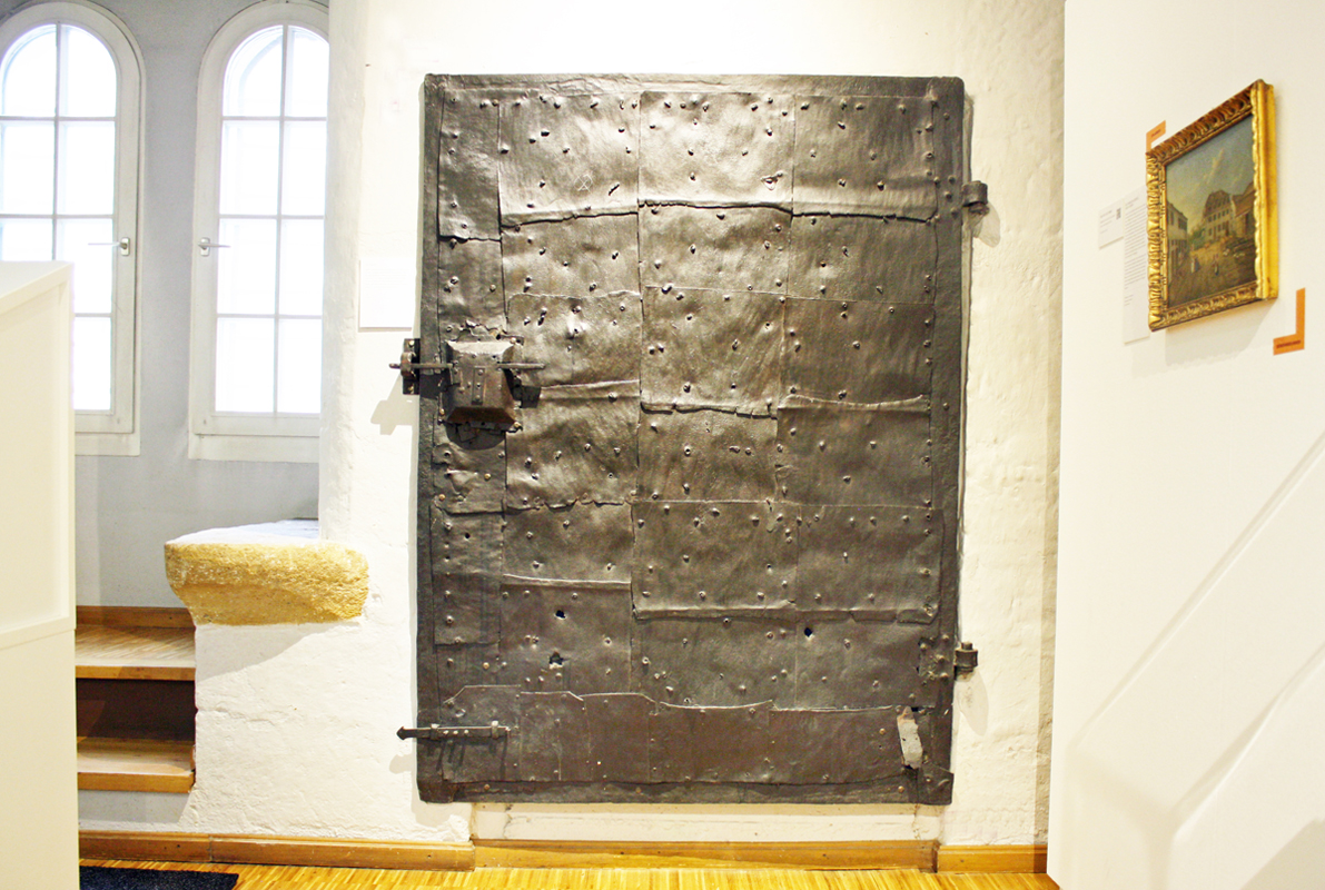 Stadtmuseum: Wand mit alter Tresortür aus beschlagenem Metall.