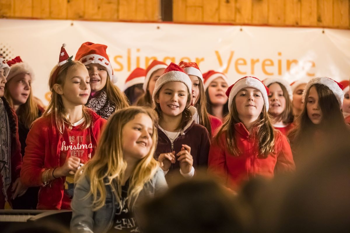 Kinder mit Nikolausmützen singen auf der Bühne auf dem Esslinger Weihnachtsmarkt
