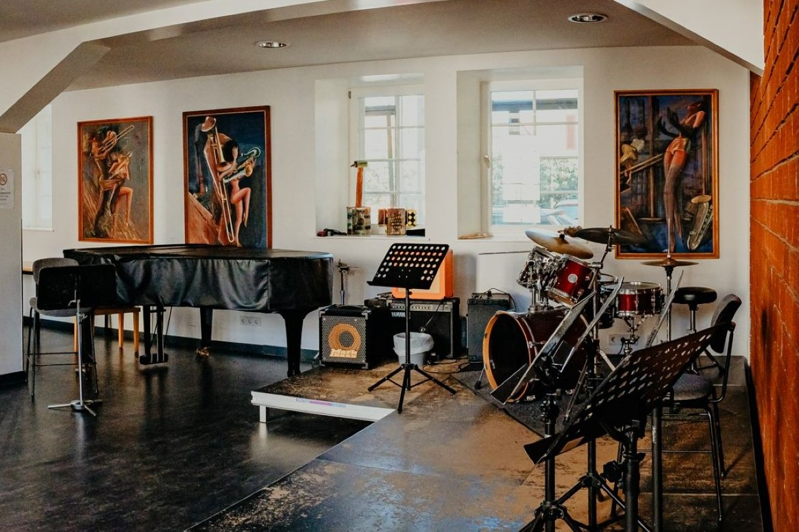 In einem Raum stehen ein Flügel und ein Podest mit Schlagzeug und Notenständer