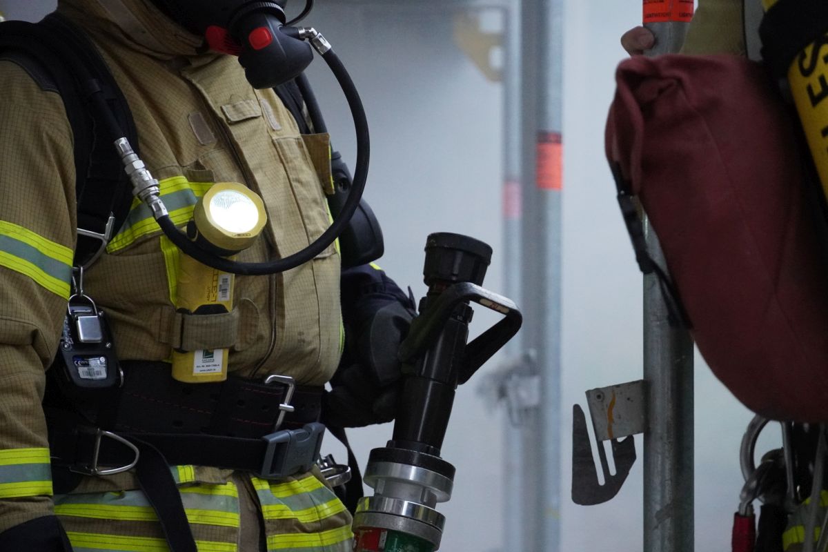 Ausgerüsteter Feuerwehrmann mit Strahlrohr in der Hand