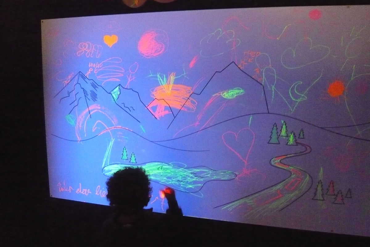 Kind malt auf eine leuchtende Wand Kind malt auf eine leuchtende Wand