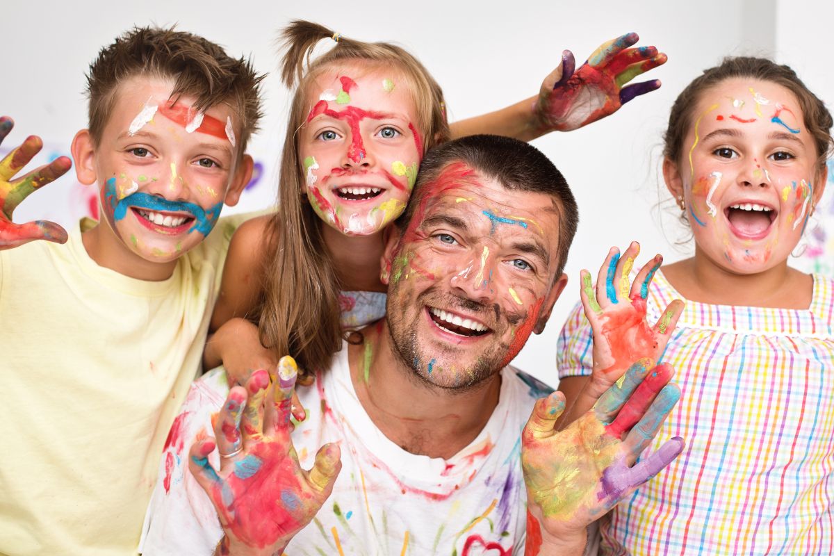 Erzieher mit Kindern, Gesichter und Hände mit bunten Farben bemalt