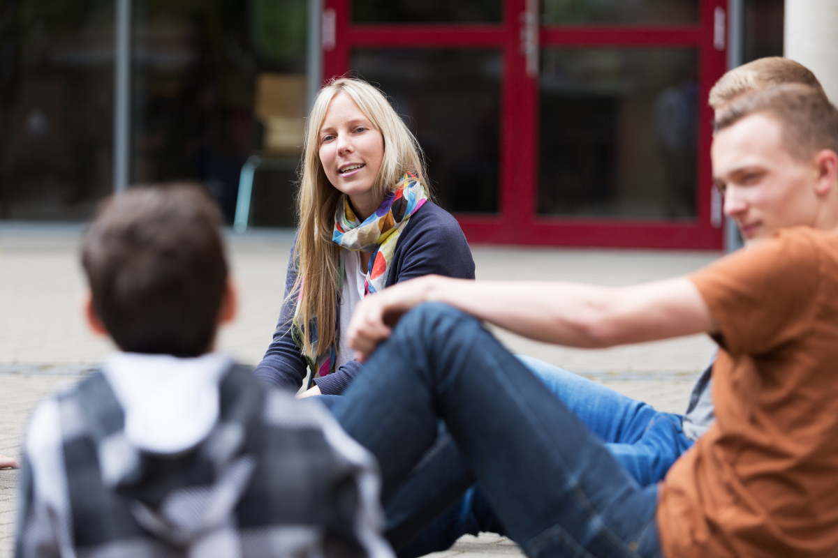 KKP Sozialarbeiterin spricht mit Jugendlichen auf dem Schulhof