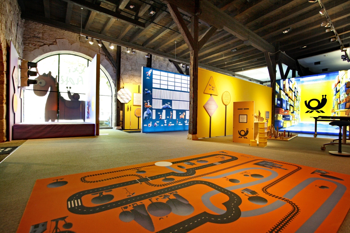 Bunte Ausstellung in historischem Raum mit interaktiven Lernstationen und kindgerechten Grafiken