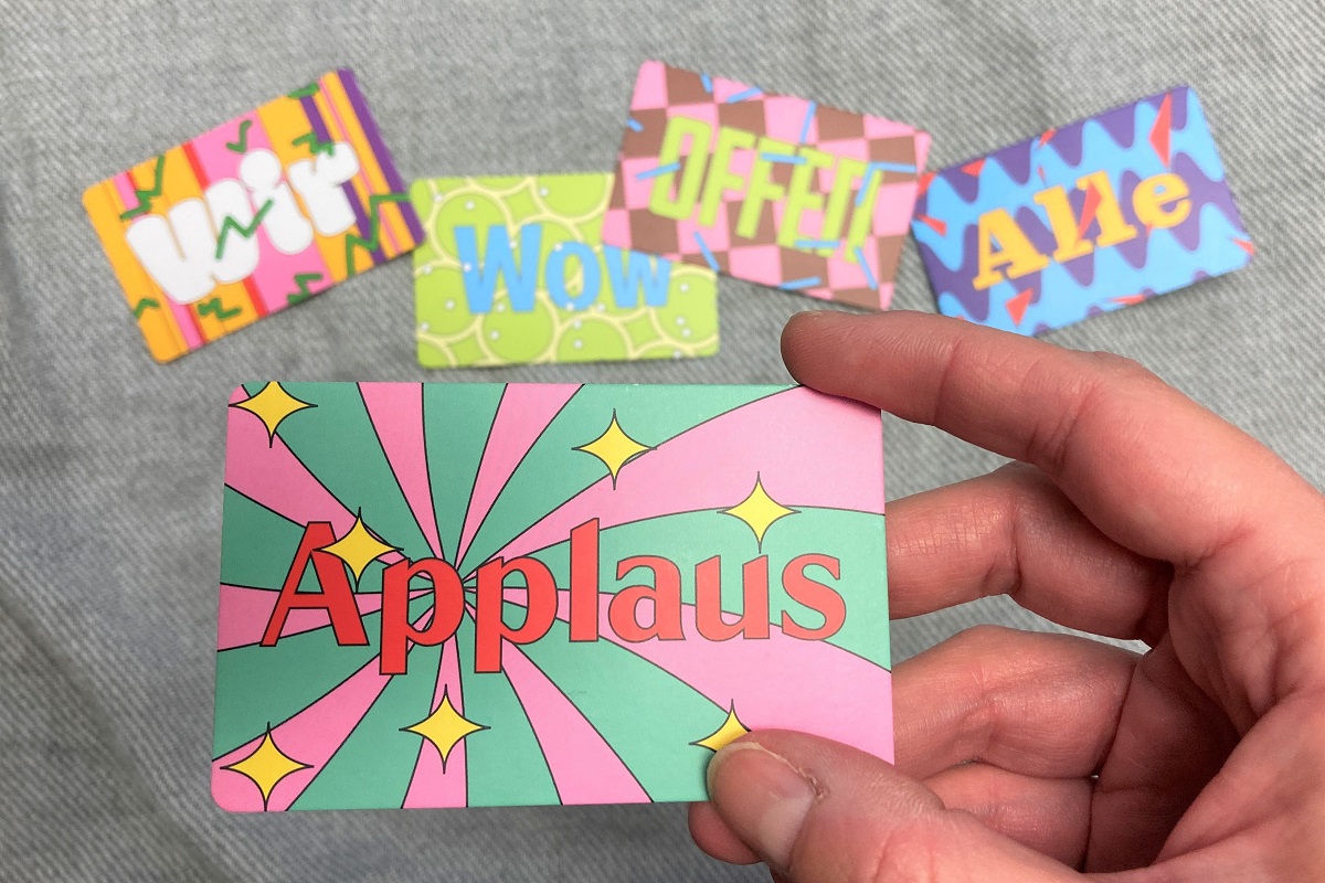 Bunte Karten im Kreditkartenformat mit den verschiedenen Aufschriften  Applaus, Wir, Wow, Offen und Alle