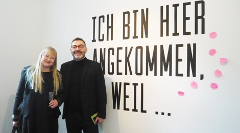 Stadträtin Regina Hemminger und Bürgermeister Yalcin Bayraktar stehen neben einer Wand, die groß beschriftet ist mit "Ich bin hier angekommmen, weil ...". Neben der Schrift kleben beschriftete Zettel.