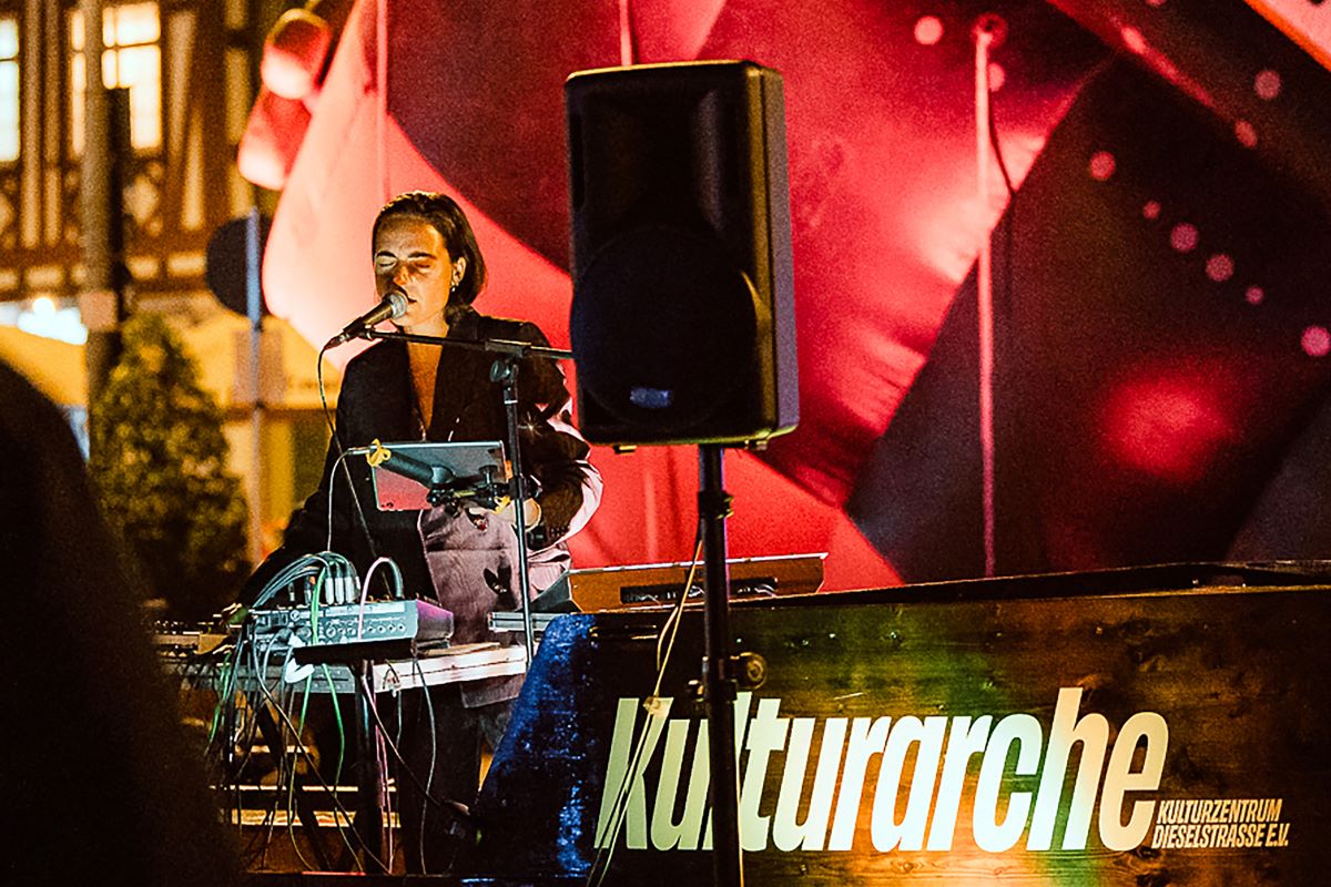 Kulturarche on tour 2025, Titelbild, © Sabine Watzko DJane auf Holzboot mit Aufschrift Kulturarche, nachts, draußen