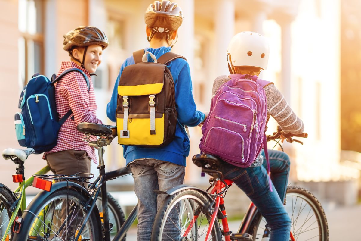 Drei Jungs mit den Rädern auf dem Weg zur Schule.