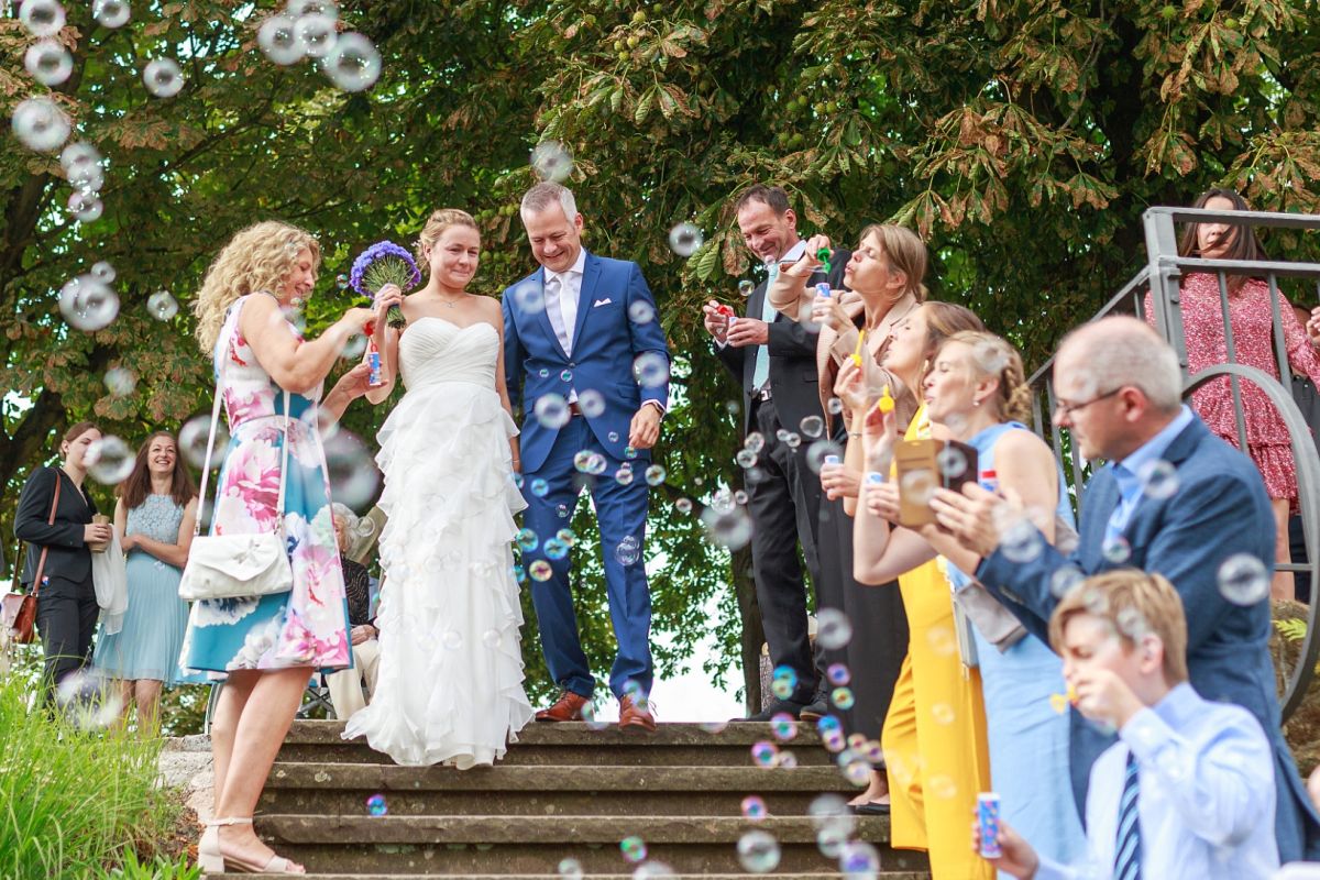 Gäste stehen mit Seifenblasen Spalier für das Brautpaar.