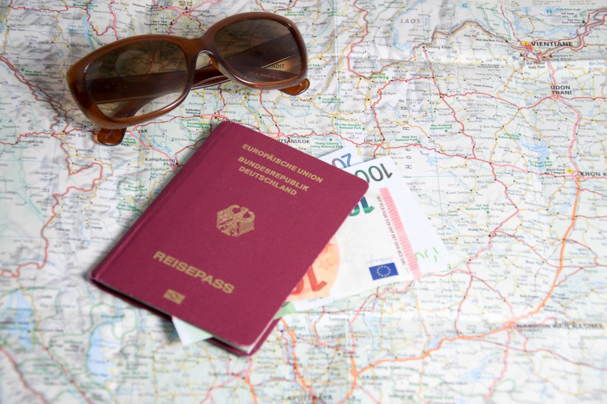 Geld, Pass und Sonnenbrille liegen auf einer Landkarte.