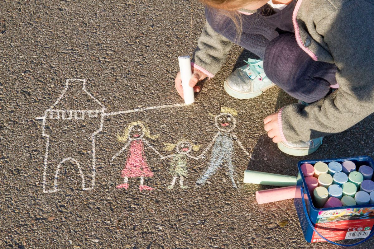 Kind malt Familie mit Straßenkreide