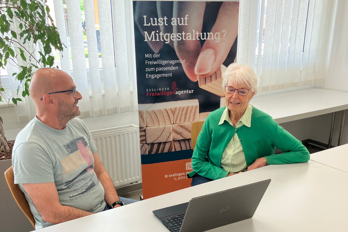 Zwei Menschen sitzen zusammen vor einem Laptop im Beratungsgespräch.